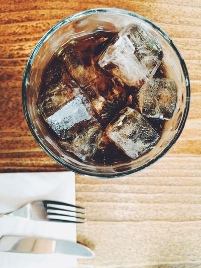 High angle view of cola in glass on wooden table