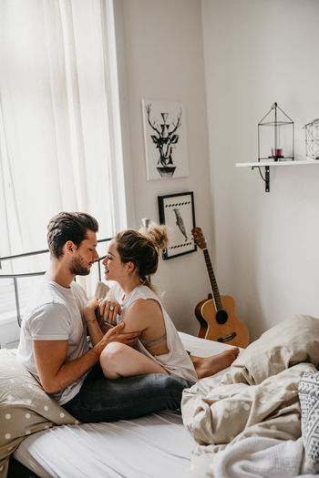 Young couple sitting on bed at home