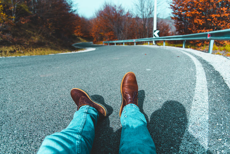 Low section of person wearing shoes on road