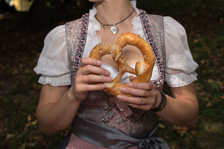 Midsection of woman holding pretzel on field