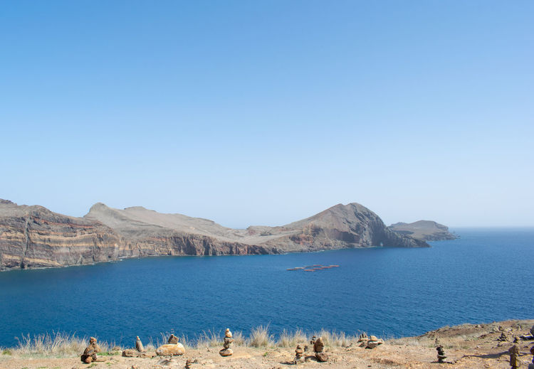 Scenic view of sea and mountains against clear blue sky