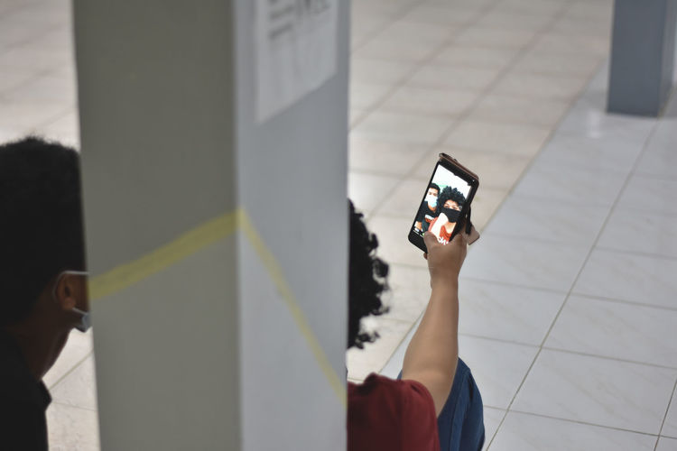 Low section of woman photographing with mobile phone on floor