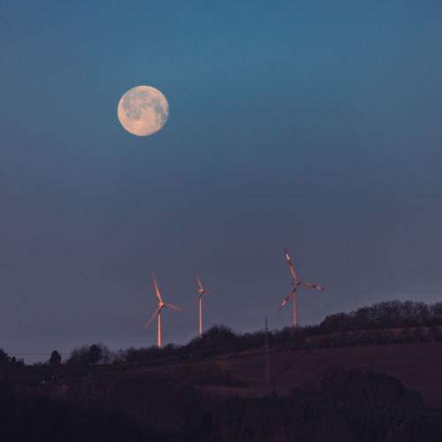 Wind turbines on land against sky at night