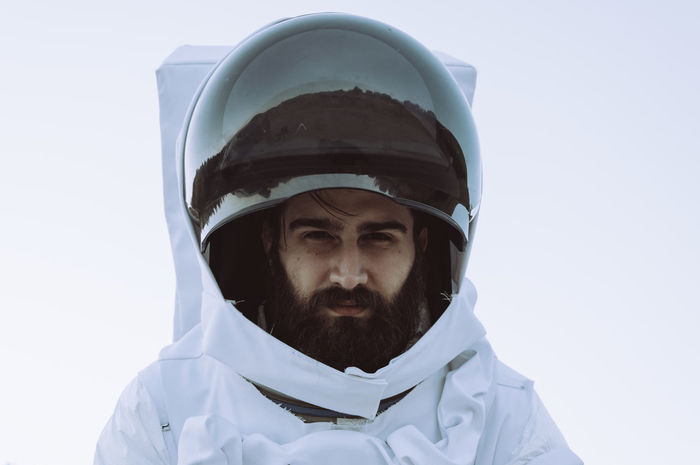 Portrait of young man in astronaut costume against white background