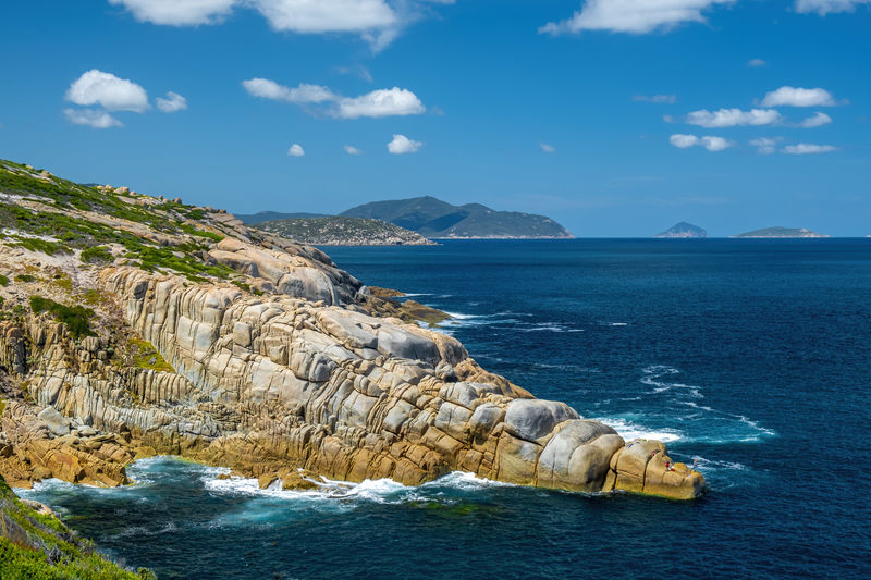 Rocky outcrops breaking ocean waves on bright summer day at wilsons prom, victoria, australia