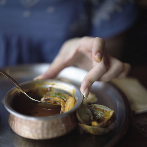 Cropped image of hand holding curry in bowl