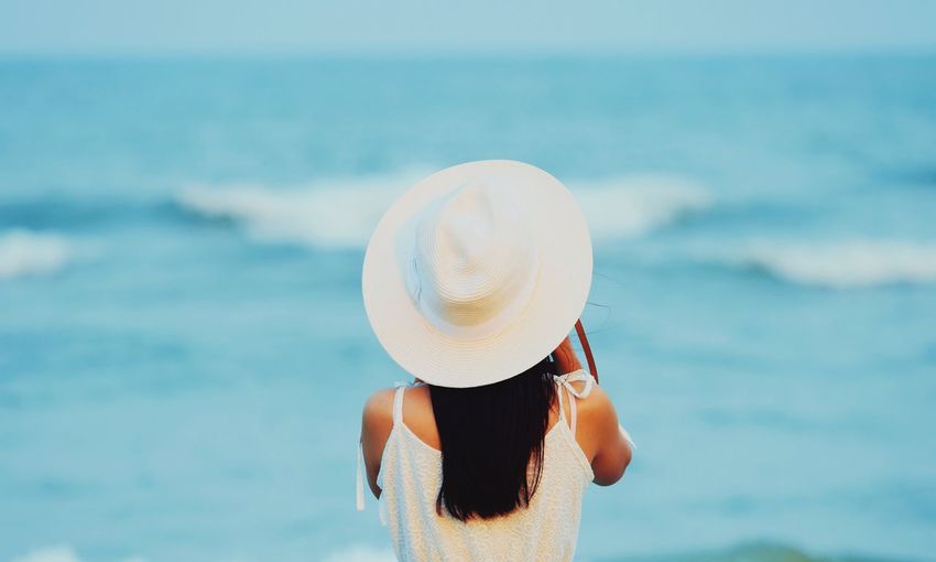 Rear view of woman in hat against sea