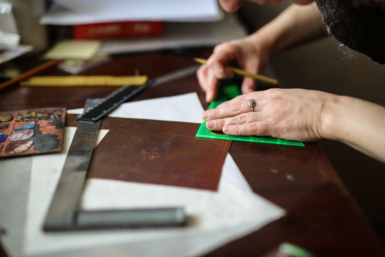 Enamel master puts a sketch on a copper plate, concept creativity and creative workshop, soft focus