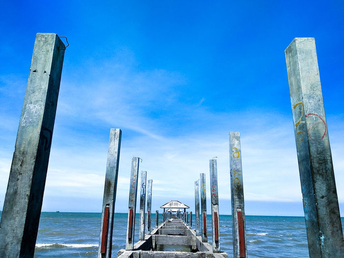 Wooden pier over sea against blue sky