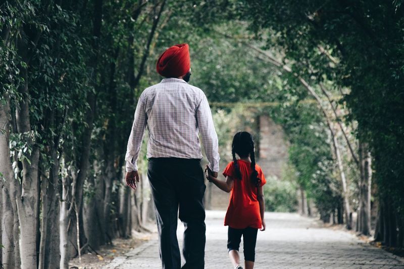 Rear view of father and daughter holding hands