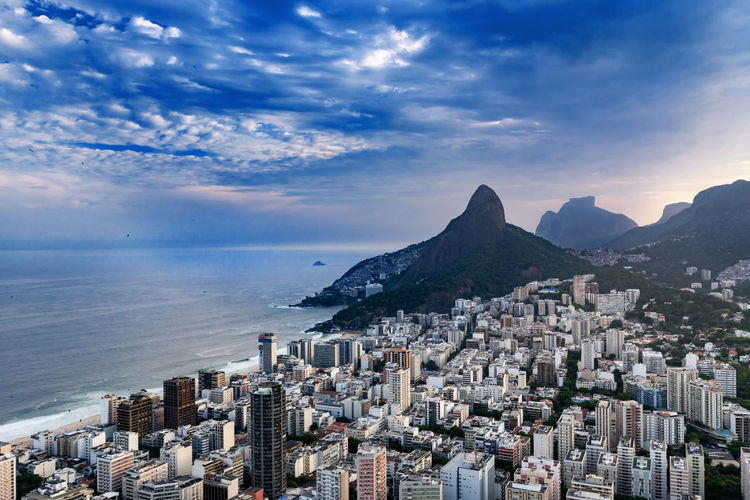 Aerial view of buildings in city by sea against sky