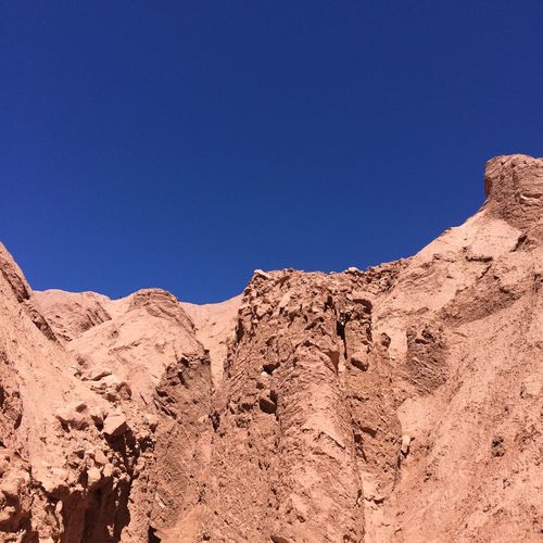 Low angle view of rocky wall against blue sky