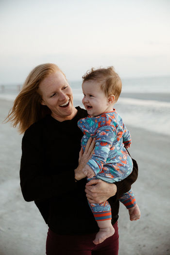 Young mother and healthy chubby boy child smile during beach walk