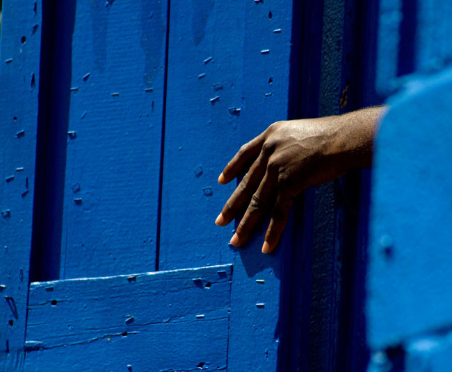 Human hand on blue shutter door
