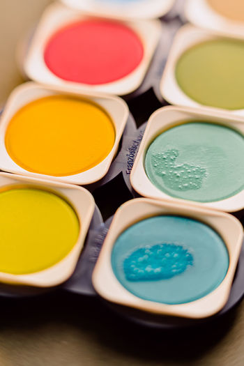 From above closeup of bright colorful watercolor paints with traces of brush arranged in box