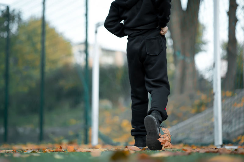 Low section of boy walking at park during autumn