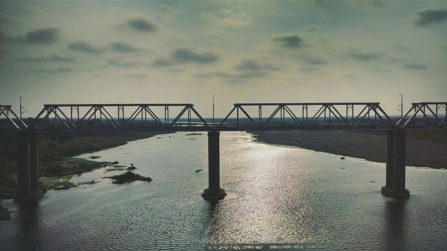 Railway bridge over river against sky