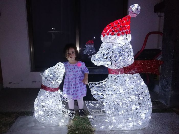 Full length portrait of cute baby girl standing by illuminated christmas decorations at home