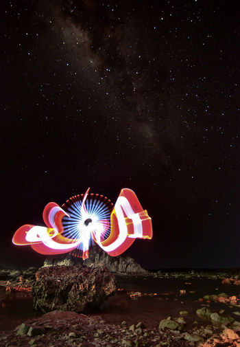 Illuminated light painting against star field at night