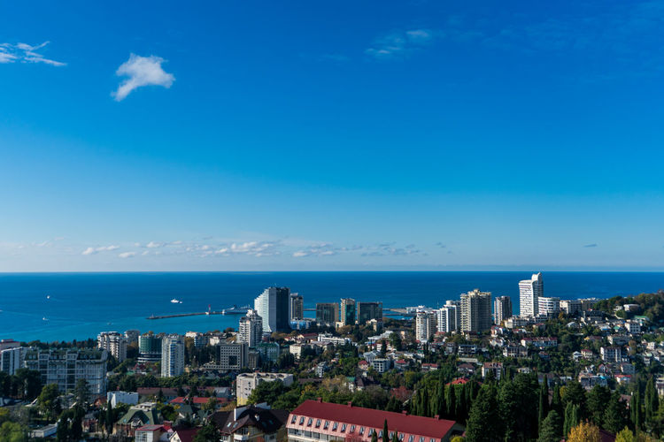 High angle view of buildings by sea against blue sky