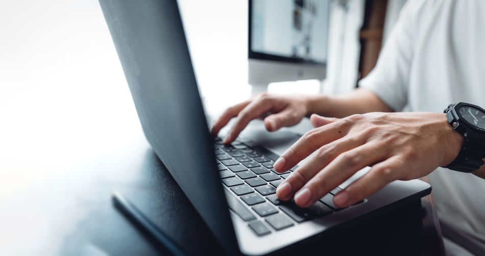 Midsection of man using laptop on table