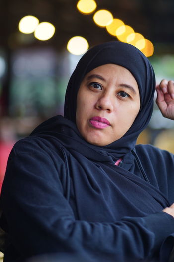 Portrait of indonesian muslim woman wearing black hijab with bokeh.