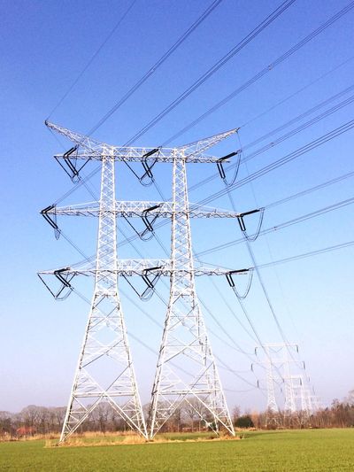 Electricity pylon on field against sky