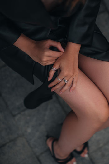 Female hands with silver rings. female body in a fashionable black leather jacket, skirt