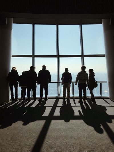 Silhouette people walking on glass window