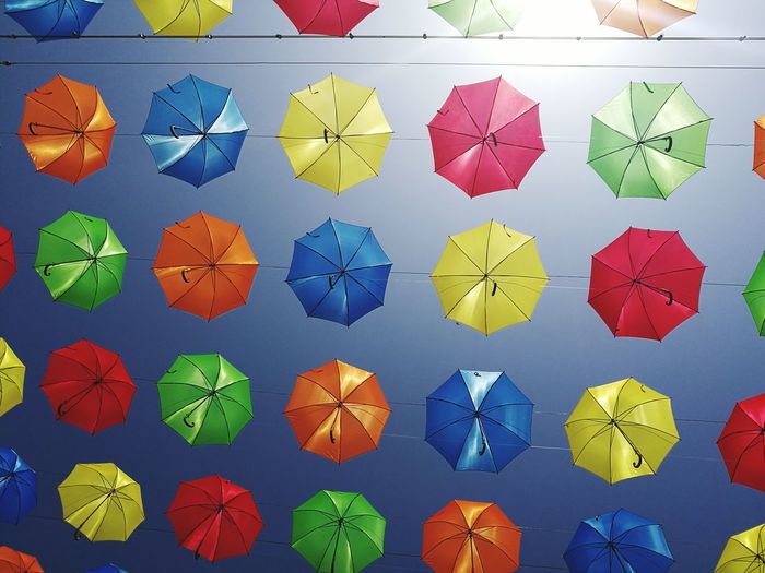 Directly below shot of colorful umbrellas hanging against clear blue sky