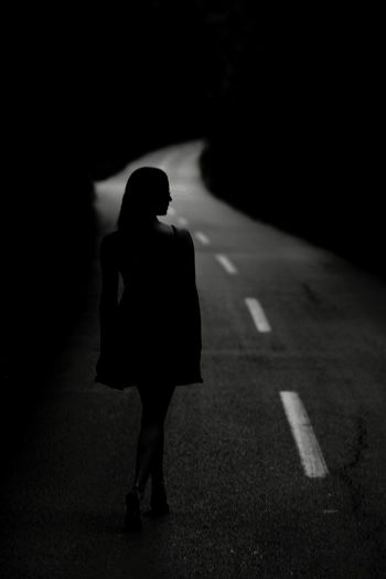 Rear view of silhouette woman walking on road