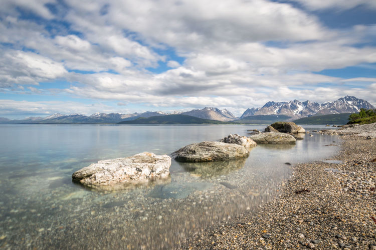 Idyllic shot of lake and lyngen alps against cloudy sky
