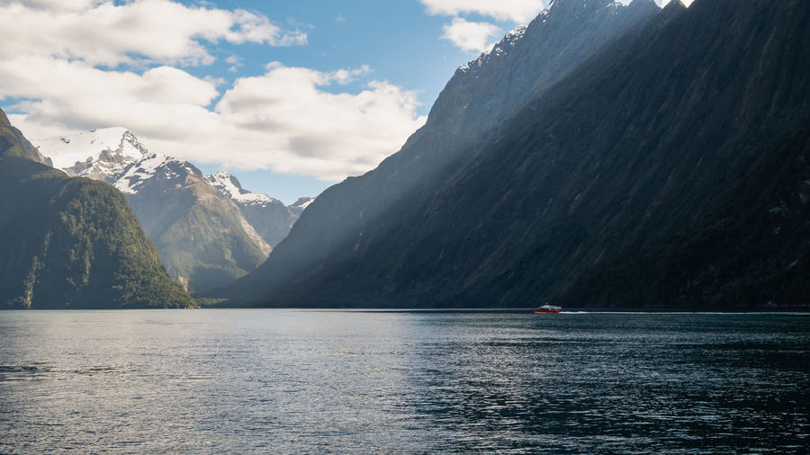 Boat sailing through fjord on a sunny day. milford sound, fiordland national park, new zealand