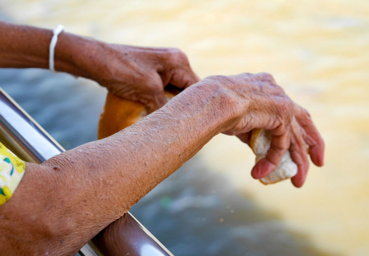 Close-up of hands holding stone against sea