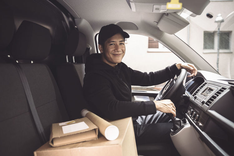 Portrait of smiling driver with package sitting in truck