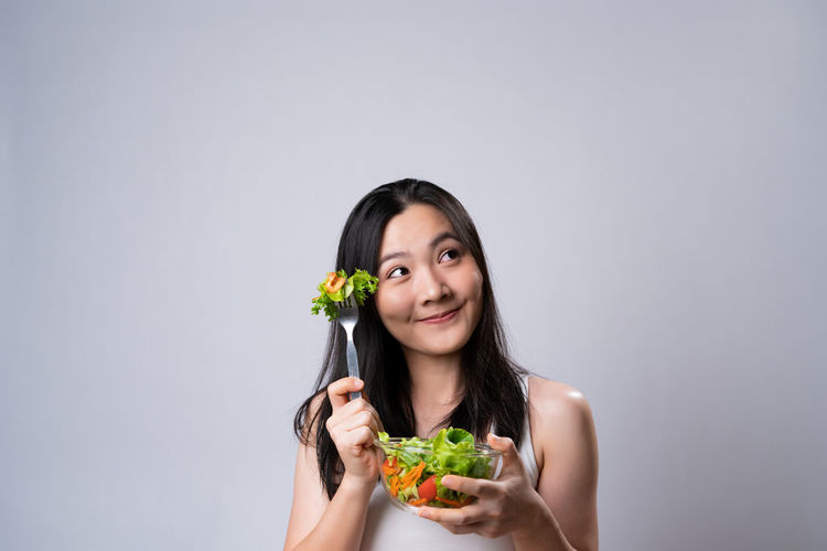 Portrait of smiling woman holding food against white background