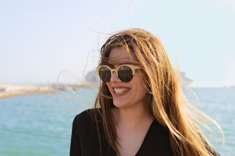 Portrait of smiling young woman against sea
