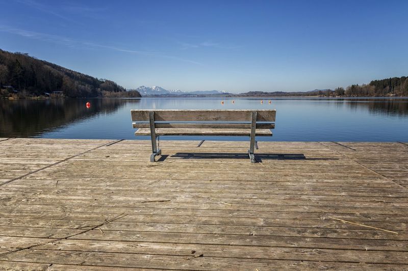 Empty pier on lake against blue sky
