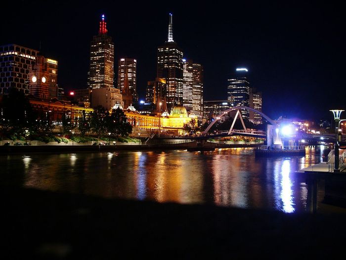 Yarra river against illuminated buildings in city at night