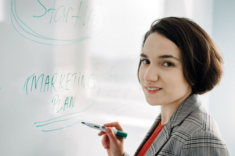 Startup business plan. young businesswoman manager, team leader, investor writing on the board