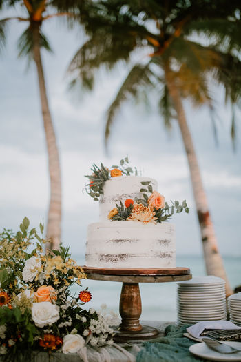 Cake on table against palm trees