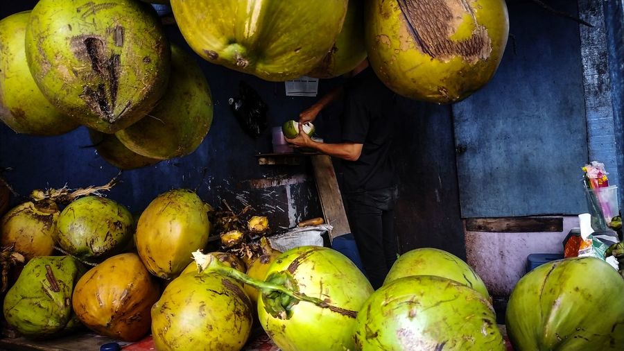 Side view of man selling coconuts at market