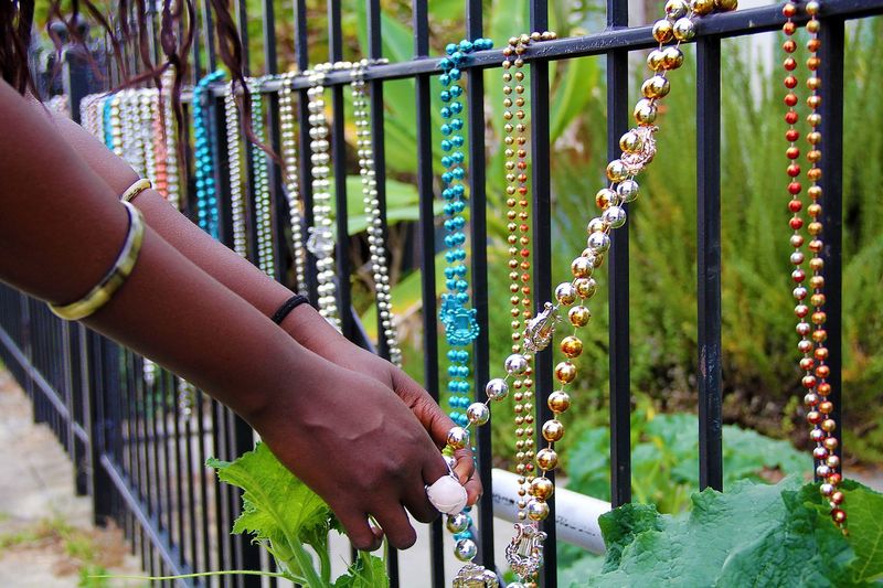 Cropped hands of woman holding bead necklace hanging on fence