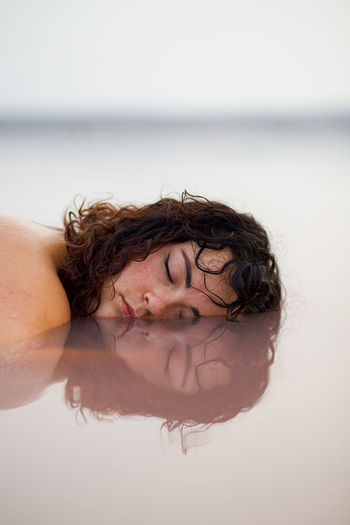 portrait of shirtless young woman swimming in sea against sky