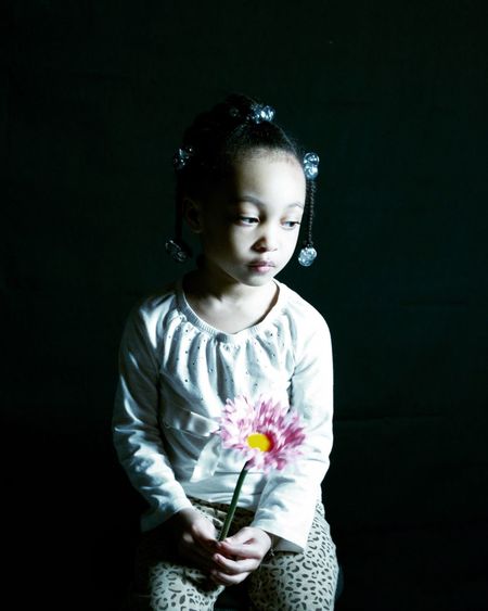 Portrait of girl with flowers against black background