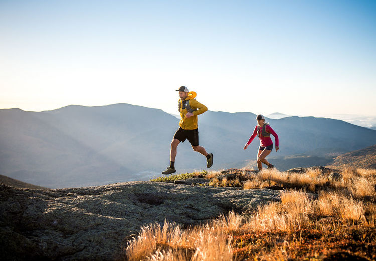 Man and woman trail running in mountains at sunrise