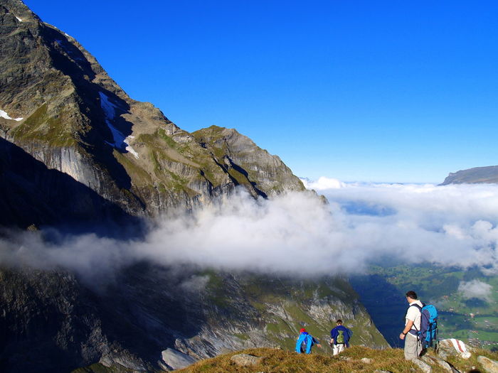 High angle view of friends walking on mountain against blue sky