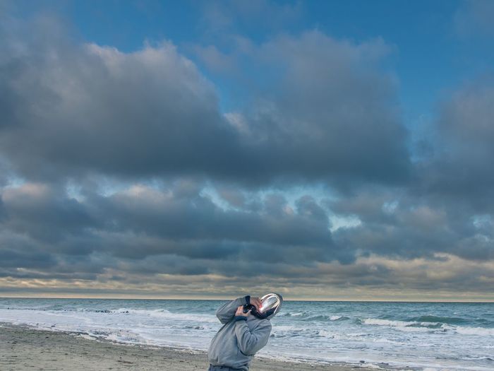 Digital composite image of man at beach against cloudy sky