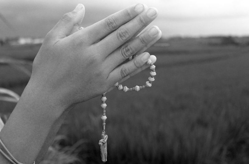 Close-up of hand holding rosary outdoors
