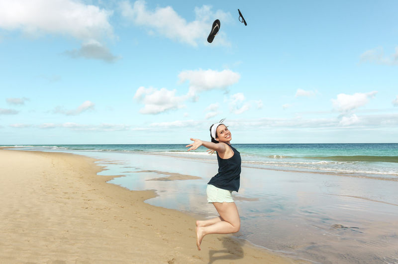 Portrait of happy woman jumping on beach